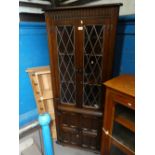 An oak corner cupboard with glazed leaded doors above cupboards