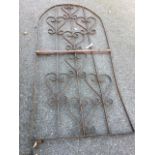 A wrought iron garden gate with scrolled decoration in arched frame. (36.5in x 79in)