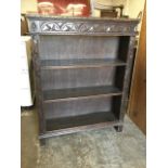 A late Victorian carved oak bookcase, the adjustable shelves framed by chisel carved stiles, beneath