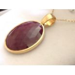An 18ct yellow gold mounted bezel set ruby pendant, the faceted oval ruby weighing over twenty