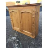 A Victorian pine cupboard with moulded cornice above panelled doors having applied split baluster