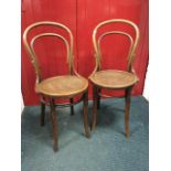 A pair of bentwood chairs having hooped backs above circular shell embossed seats, raised on