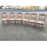 A set of six late Victorian carved oak dining chairs, the back rails with foliate scrolled carving