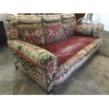 An Edwardian three-seater sofa, upholstered in antique kelim fabric with padded arms and sprung