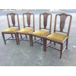 A set of four Edwardian mahogany dining chairs, the arched boxwood strung backs above pierced urn