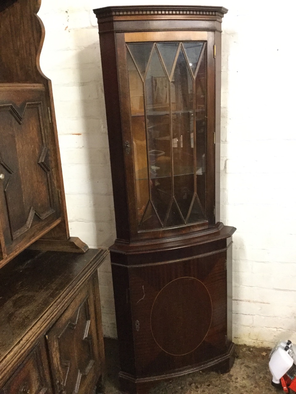 A mahogany corner cabinet with dentil cornice above astragal glazed door, the base with cupboard