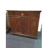 A mahogany cabinet with lifting top having dentil moulding and frieze inlaid with circular shell