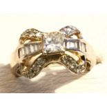 A 14ct gold diamond bow ring, with stones both baguette & brilliant cut, around a raised central