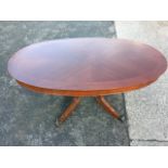 An oval mahogany coffee table, the crossbanded quarter veneered top on bulbous turned column, raised