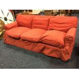 A three-seater sofa with linen loose covers and cushions, raised on square legs with casters. (