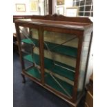 An Edwardian mahogany display cabinet with shaped upstand on rectangular moulded top above