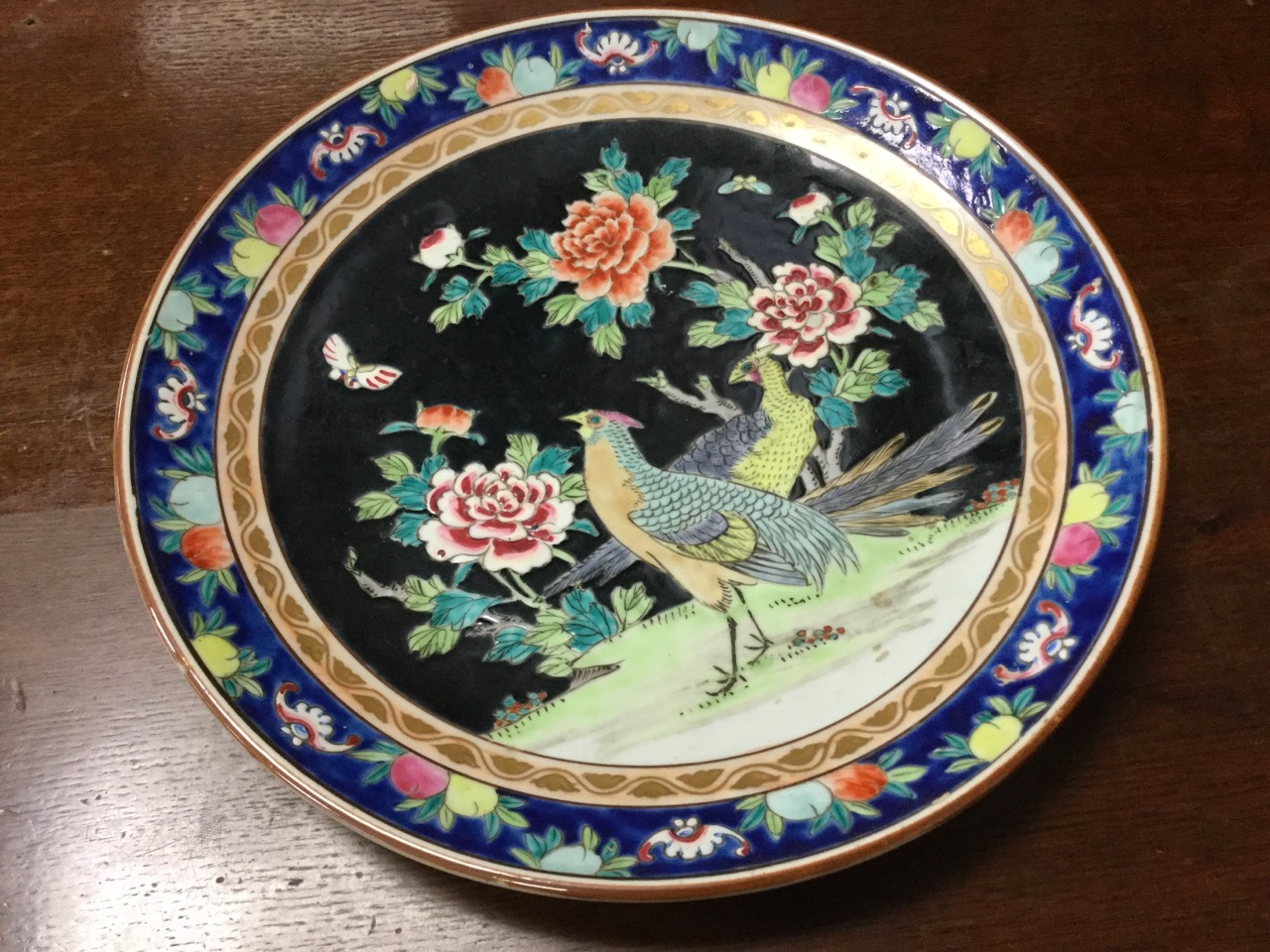 A porcelain charger decorated in an oriental palette with exotic birds, prunus blossom and