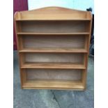 A satin walnut open bookcase with arched back above five graduated shelves, supported on a