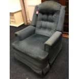 An upholstered reclining and rocking armchair, the button upholstered back above a loose cushion,