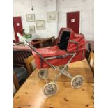 A 70s childs toy pram with vinyl detachable carrycot and cover, having concertina hood.