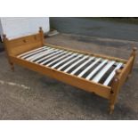 A pine single bed with plain side rails and slatted base, the ends with moulded rails having