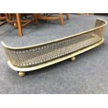 A Victorian brass fender of 'D' shaped outline with tubular rail above pierced grill on moulded curb