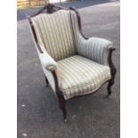 A late Victorian mahogany saloon armchair, the upholstered back beneath pierced scroll carved rail