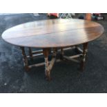 A large oval oak wake table, with two drop leaves each supported on twin gates, the bobbin turned