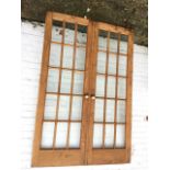A pair of pine doors, each with fifteen bevelled glass panes in moulded frames, mounted with brass