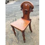A Victorian mahogany hall chair, the back with scrolled carving having applied shield, the