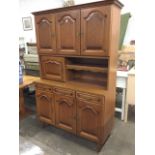 A French oak dresser with moulded cornice above three arched fielded panelled cupboards, having open