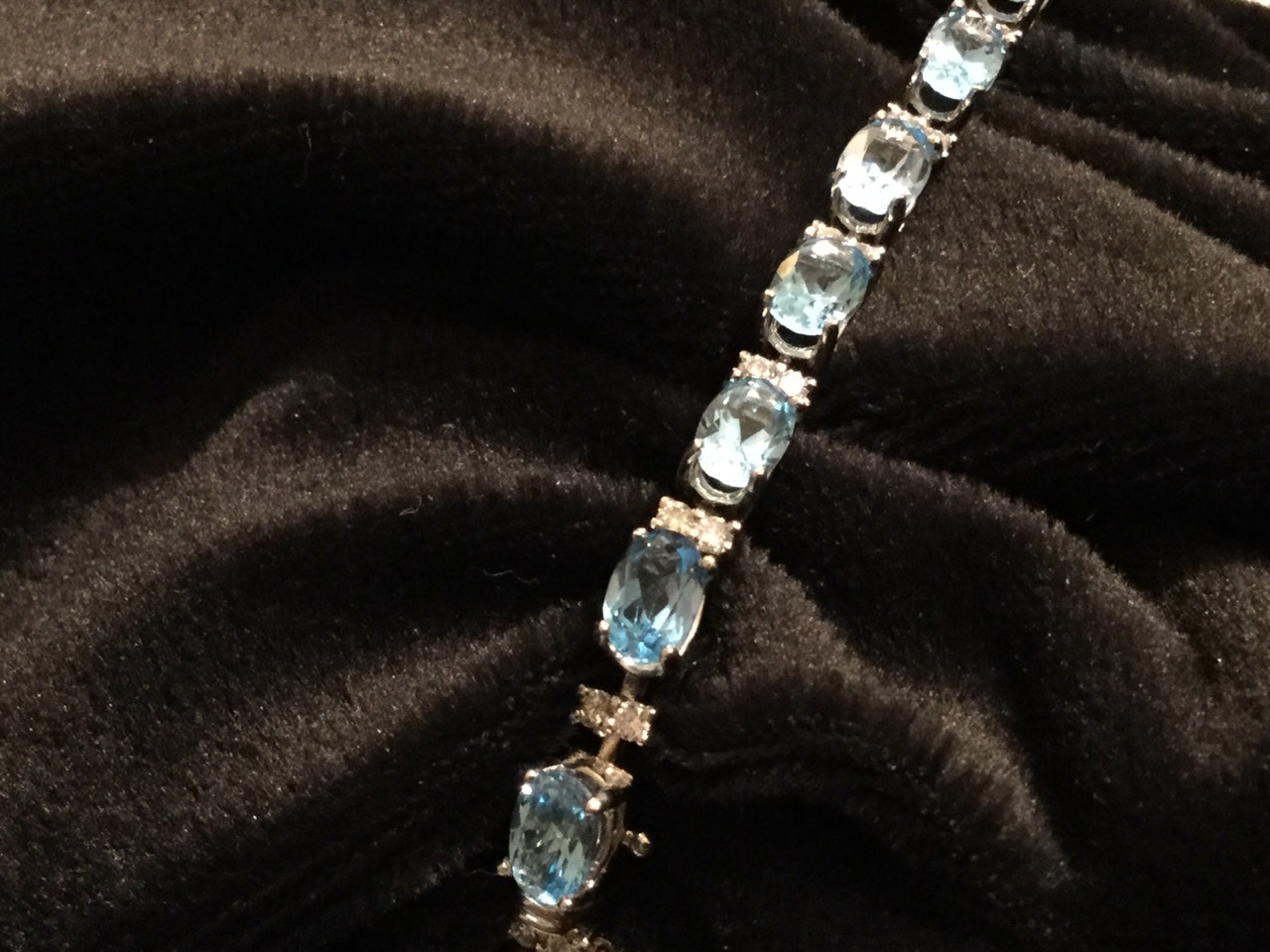 An 18ct gold blue topaz and diamond bracelet, with twenty one claw set topaz stones weighing