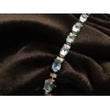 An 18ct gold blue topaz and diamond bracelet, with twenty one claw set topaz stones weighing