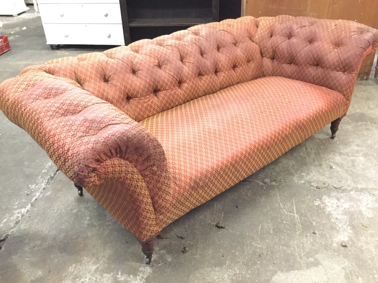 A Victorian chesterfield sofa with button upholstery and sprung seat, raised on turned tapering