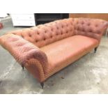 A Victorian chesterfield sofa with button upholstery and sprung seat, raised on turned tapering