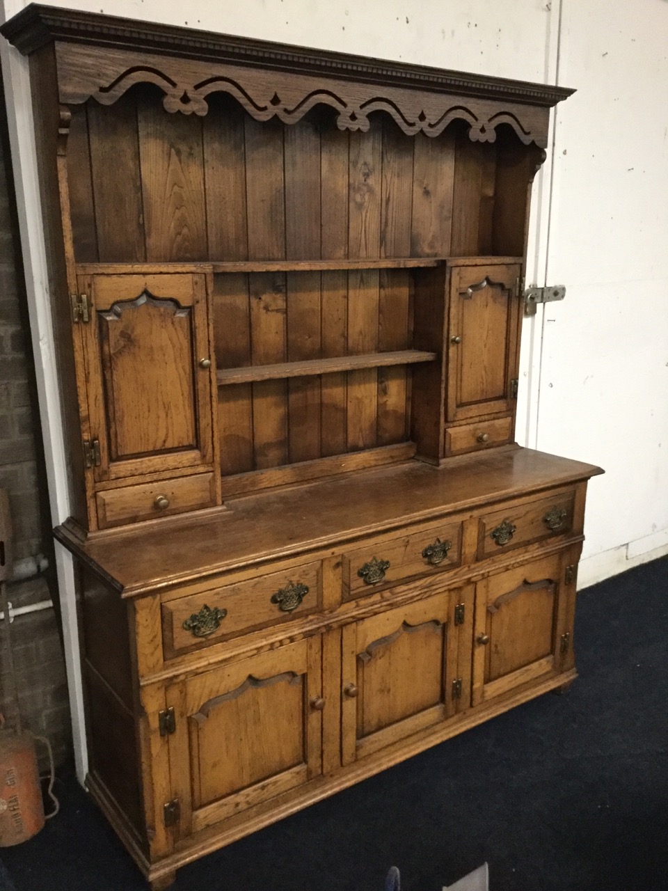 A Georgian style oak dresser, the delft rack with dentil cornice above a pierced waved apron, having