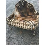 A cast iron dog grate with scroll-cast fireback behind rectangular grill framed by scrolled bars,