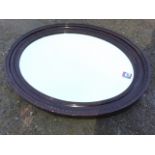 An Edwardian oval mirror, the bevelled plate in lozenge moulded frame.