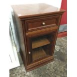 A Gplan cabinet with panelled frieze drawer above a glazed cupboard with adjustable shelf, supported