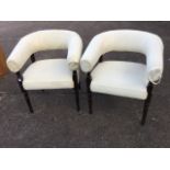 A pair of upholstered tub armchairs, with rounded padded back rails above sprung seats, raised on