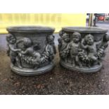 A pair of circular composition stone garden tubs, the pots cast with continuous friezes of winged