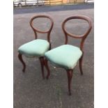 A pair of Victorian walnut balloon-back dining chairs with stuffover upholstered seats raised on