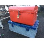 A red painted domed top tin trunk with studding to lid, having carrying handles to ends; and a