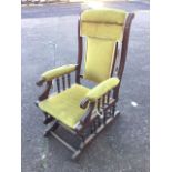 An American style rocking chair, with upholstered back framed by moulded stiles above padded