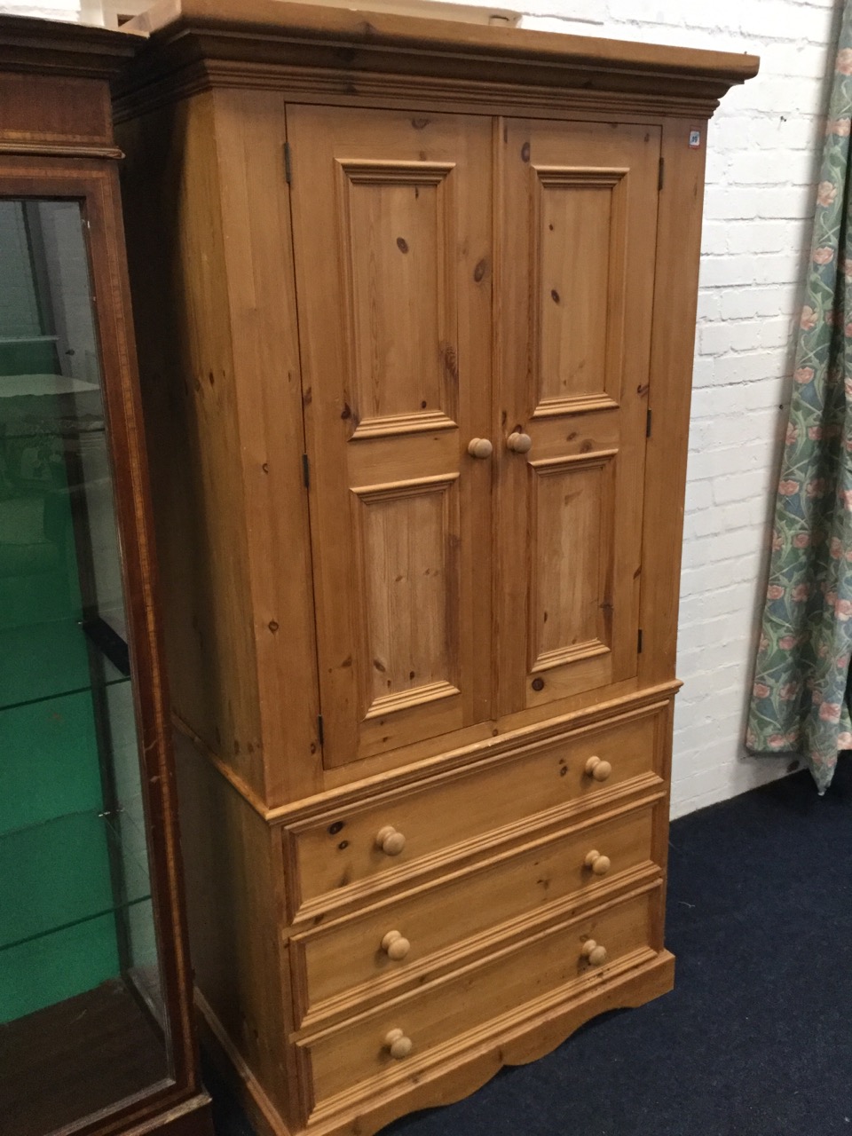 A Victorian style pine press with moulded cornice above panelled doors enclosing hanging space,