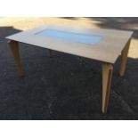 A contemporary beech dining table with shaped tapering legs, the rectangular top inset with etched