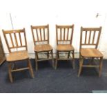 A set of four school type elm seated slatback chairs, the solid seats raised on turned legs &