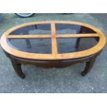 An oval contemporary burr elm coffee table, the moulded top with four bevelled glass panels above