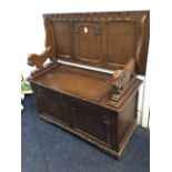 An oak monks bench, the folding moulded tabletop having three chamfered panels beneath a rail carved