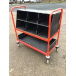 A rectangular post office trolley with compartments for sorting mail in tubular frame on casters. (