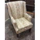 An American Georgian style wing armchair, upholstered in tapestry style floral fabric having