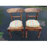 A pair of Victorian mahogany dining chairs with shaped back rails above solid seats with loose