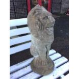 A composition stone lion alertant, the beast sitting on his haunches above circular plinth. (20in)