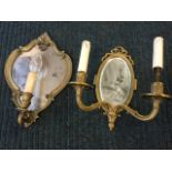 A brass wall sconce with oval bevelled mirror back and two scrolled branches holding candlelights;
