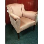 An Edwardian upholstered armchair with padded back and arms above a sprung seat, raised on square